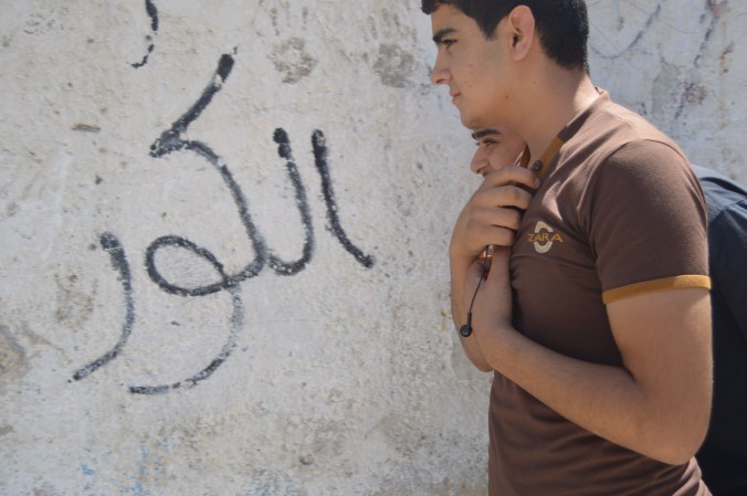 Taseer, one of our students, walks by neighborhood wall. 